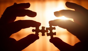 Two hands holding puzzle pieces conveying partnership solutions